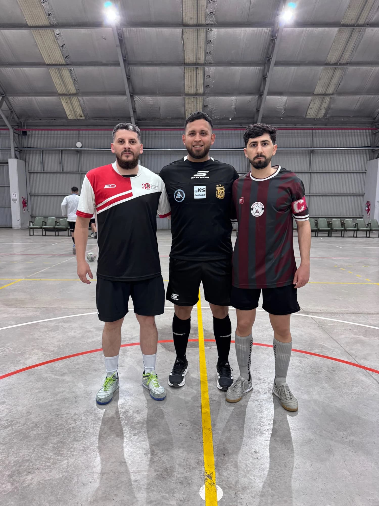 Capitanes de UNQ y UNLa Granate junto al árbitro